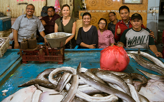 A group standing across a table with fish. A group standing across a table with fish.
